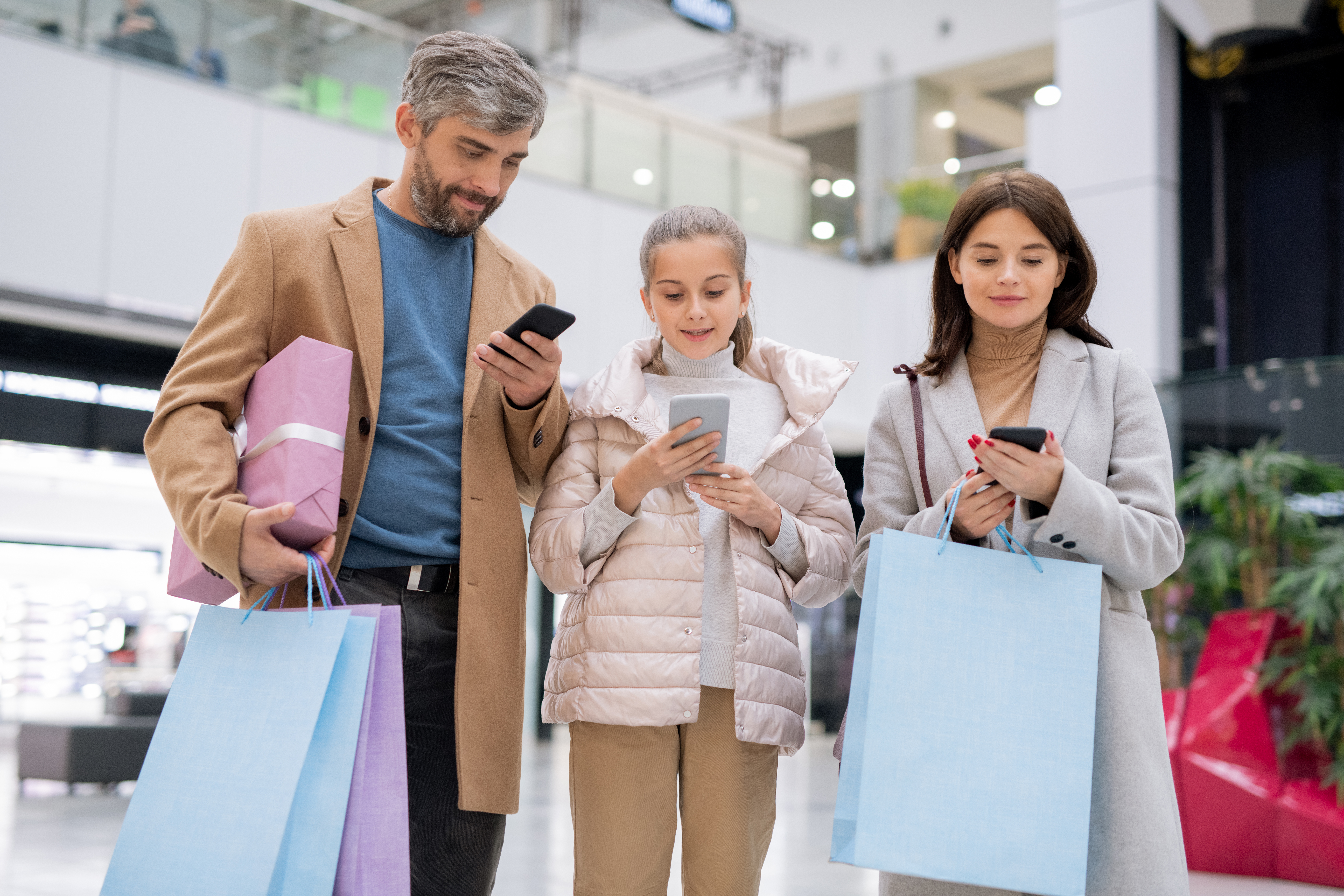 Family playing a campaign game on their phone in a modern shopping mall